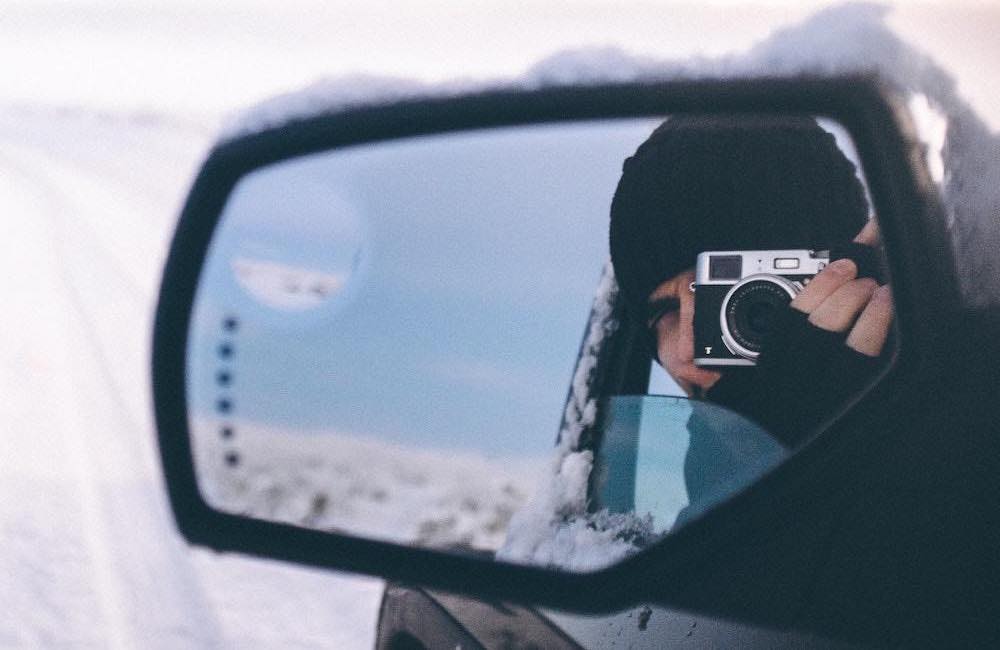 Observación de un fotógrafo en el espejo lateral de un coche